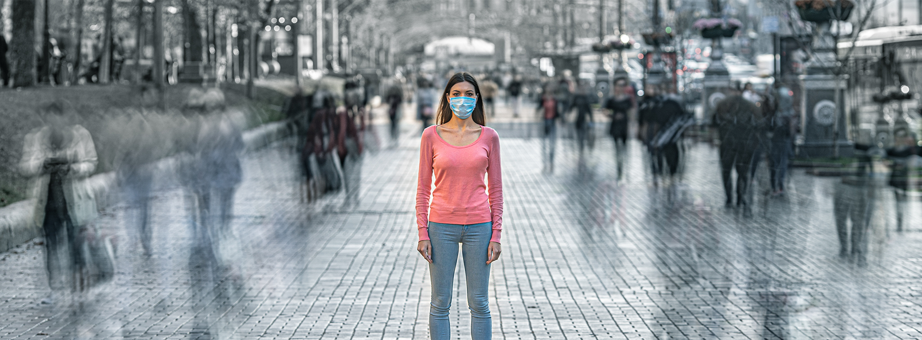 Young person with medical mask on face, standing on a crowded street